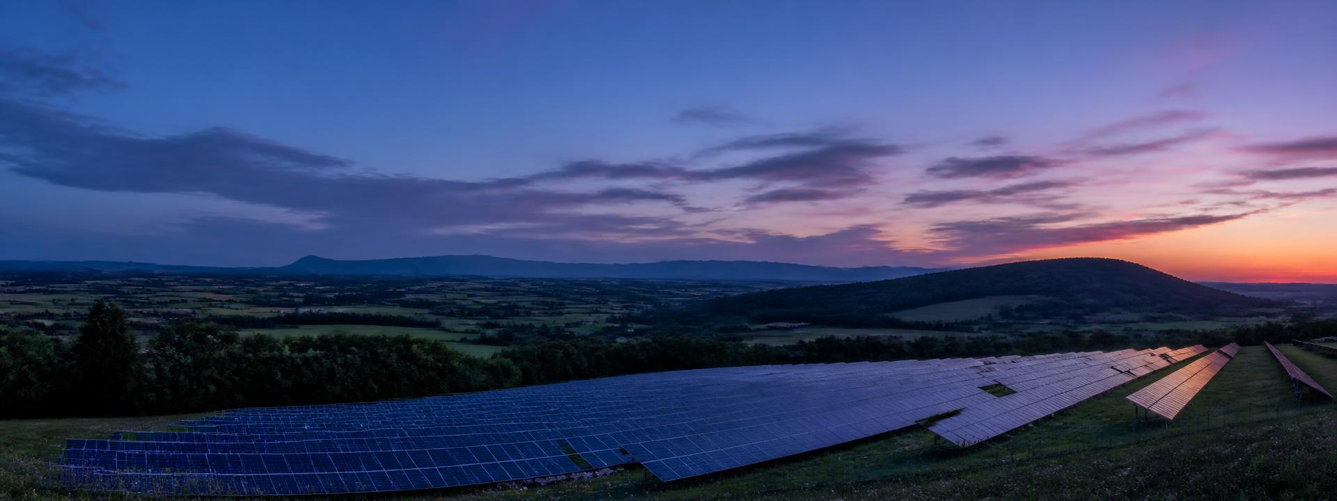 Freiflächen-Solaranlage in einer deutschen Hügellandschaft in der Abenddämmerung